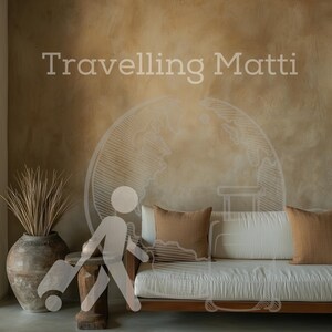 Puede incluir: Un sofá blanco con cojines marrones en una habitación con una pared de color marrón texturizada. El texto "Travelling Matti" está escrito en la pared.