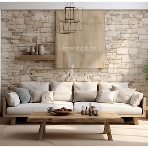 May include: A white sofa with multiple cushions sits in front of a stone wall with a wooden shelf and decorative items. A wooden coffee table with a bowl of fruit and decorative bottles sits in front of the sofa. The text "Travelling Matti" is visible on a canvas hanging on the wall.