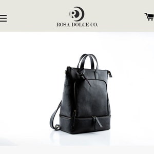 Peut inclure: Sac à dos en cuir noir avec une poignée supérieure et une poche avant zippée. Le sac à dos a un compartiment inférieur avec une fermeture éclair et un petit logo sur le devant.