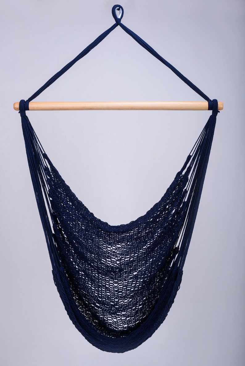 Puede incluir: Una silla hamaca de color azul marino colgando de una barra de madera. La hamaca est&aacute; hecha de un material de cuerda trenzada.