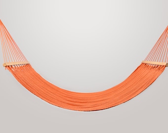 May include: An orange hammock with wooden spreader bars hangs against a white background.