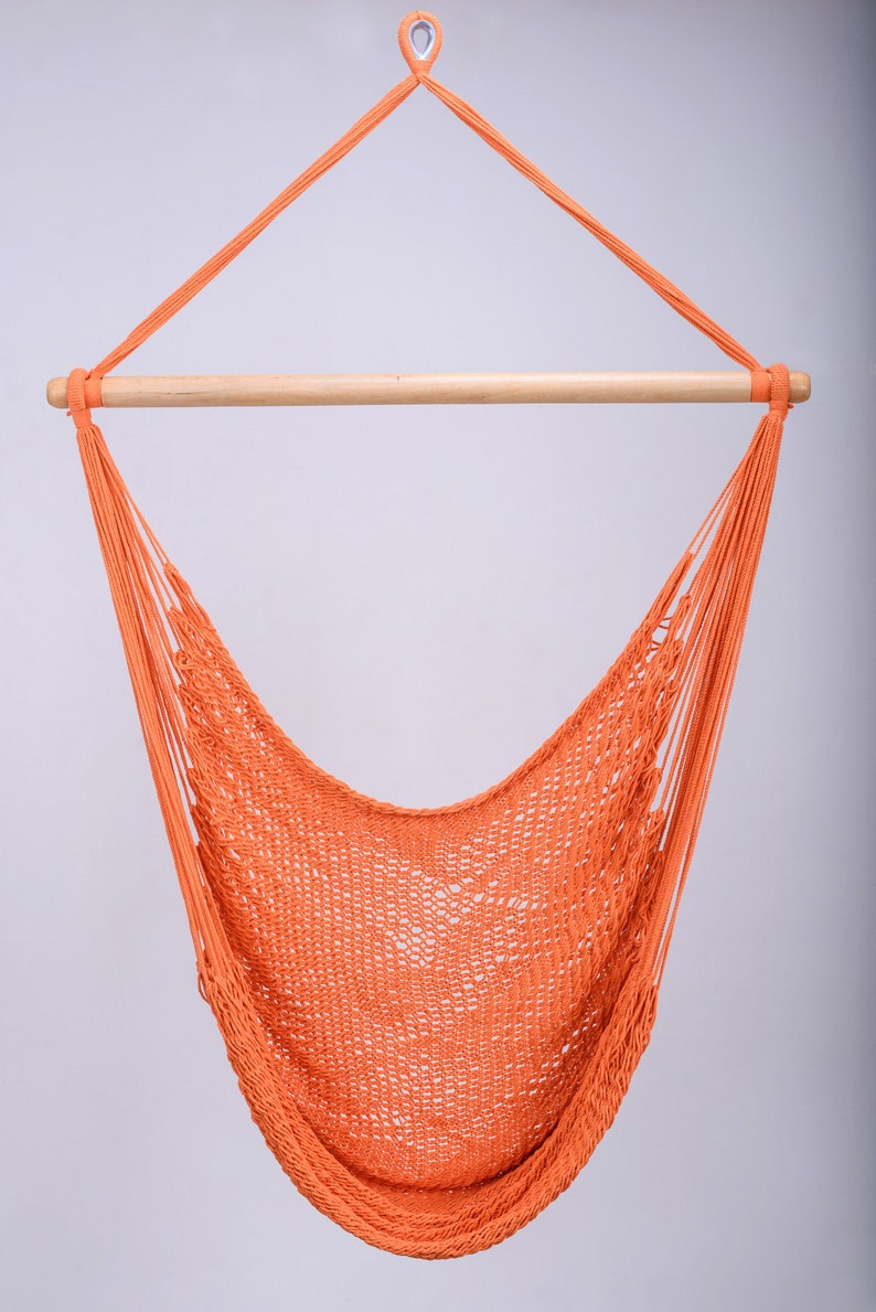 Puede incluir: Una silla hamaca naranja colgando de una barra de madera. La hamaca est&aacute; hecha de un material de cuerda trenzada.