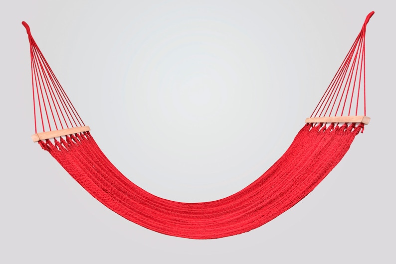 May include: A red hammock with wooden spreader bars. The hammock is made of woven rope and is hanging from two points.