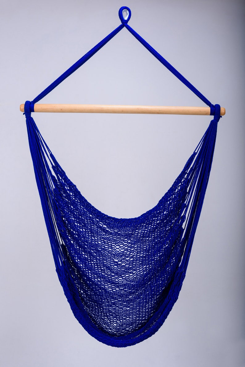 Puede incluir: Una silla hamaca azul con una barra de extensi&oacute;n de madera. La hamaca est&aacute; hecha de material de cuerda tejida y est&aacute; colgada de un lazo en la parte superior.