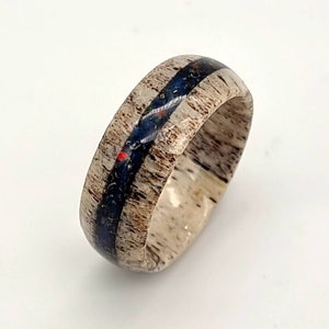May include: A ring made of antler with a blue and black inlay. The ring has a natural wood grain pattern.