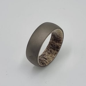 May include: A gray titanium ring with a brown antler inlay.