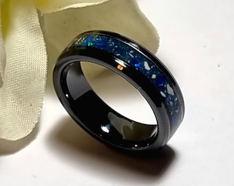 May include: A black ceramic ring with a blue and white opal inlay. The ring is polished and has a smooth finish.
