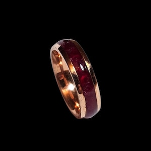 Könnte beinhalten: Ein Roségold-Bandring mit einer dünnen roten Einlage.
