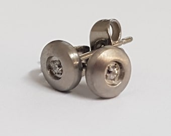 Könnte beinhalten: Ein Paar silberne Ohrstecker mit einem kleinen, klaren Stein in der Mitte jedes Ohrsteckers.