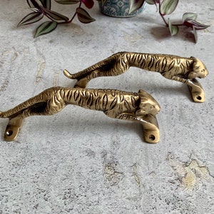 May include: Two gold-toned tiger-shaped door handles. The handles are detailed with a tiger stripe pattern and have a realistic tiger head design.