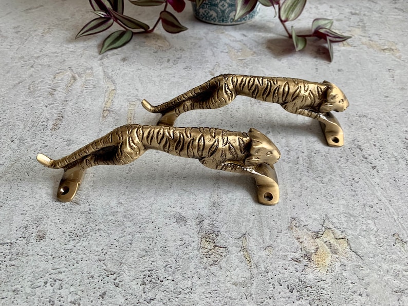 May include: Two gold-toned tiger-shaped door handles. The handles are detailed with a tiger stripe pattern and have a realistic tiger head design.