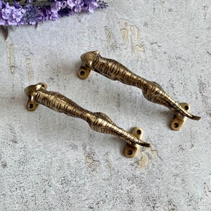 May include: Two brass door handles shaped like a crouching tiger. The handles are detailed with a tiger stripe pattern and have a gold finish.