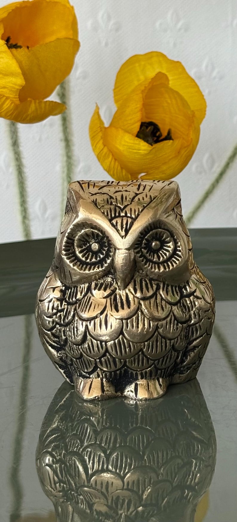 May include: A small, gold-colored owl figurine with detailed feather patterns. The owl has large, round eyes and a beak.