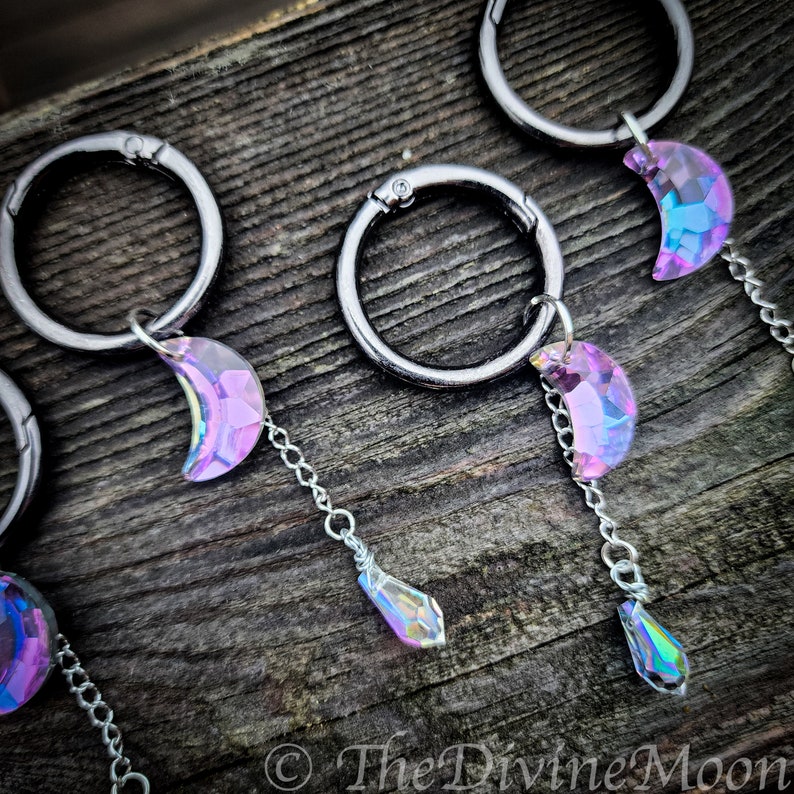 May include: Four silver keyrings with iridescent purple crescent moon charms and teardrop crystals hanging from them.