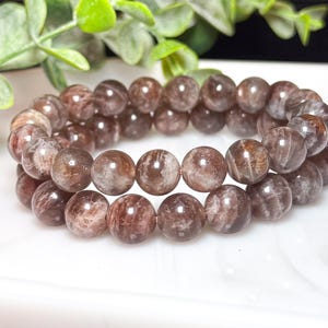 May include: A double-strand bracelet made of light brown and grey gemstone beads. The beads are round and have a smooth, polished finish.