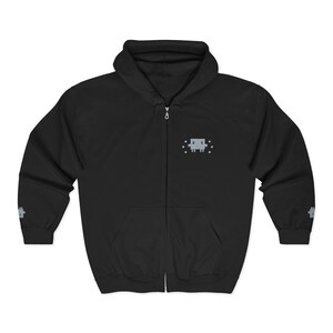 May include: Black zip-up hoodie with a pixelated gray alien design on the chest. The hoodie features a drawstring hood, a full-length zipper, and two front pockets. The sleeves have a small gray pixelated design near the cuffs.