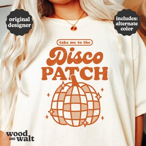 May include: A white t-shirt with the text "take me to the Disco Patch" in orange and brown lettering. The text is above a pumpkin-shaped disco ball with orange and brown accents.