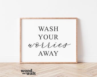 Może przedstawiać: Prostokątny wydruk ścienny w jasnej drewnianej ramie z czarnym napisem WASH YOUR worries AWAY na białym tle. Słowo worries jest napisane kursywą, podczas gdy pozostałe słowa są zapisane pogrubioną czcionką szeryfową.
