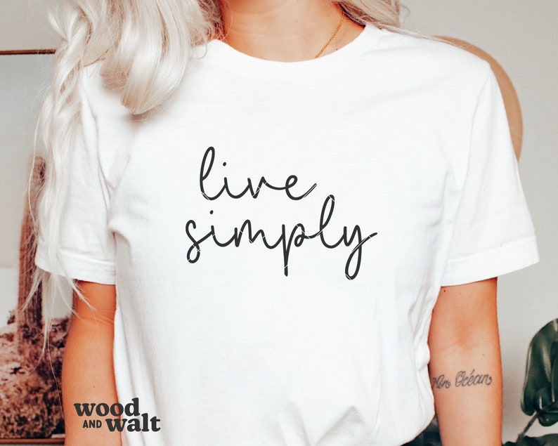 May include: White t-shirt with the text "live simply" written in black cursive script.