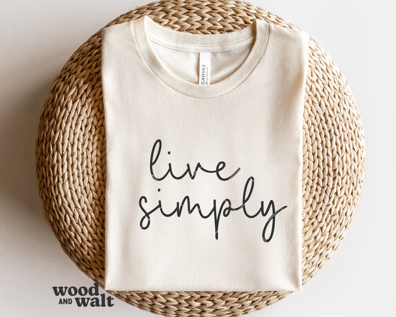 May include: A white t-shirt with the text "live simply" written in black cursive script.