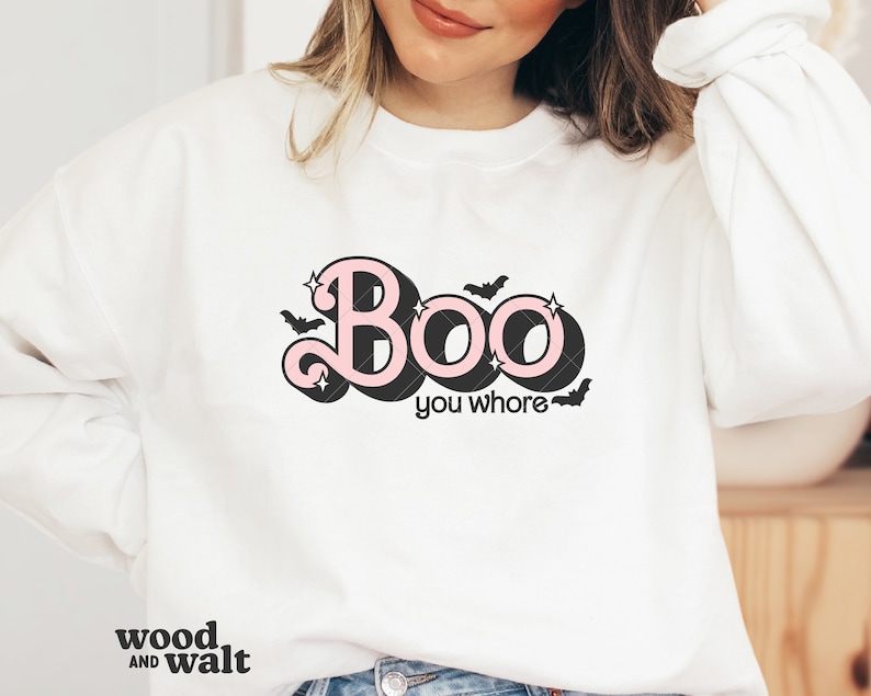 May include: White sweatshirt with the text "Boo you whore" in a pink and black design. The word "Boo" has a retro font with stars and bats. The sweatshirt is a crew neck style.