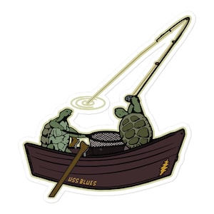 May include: A sticker featuring two green turtles fishing from a brown boat. One turtle rows with a wooden oar, while the other holds a fishing rod. The boat has the text "USS BLUES" and a lightning bolt design.