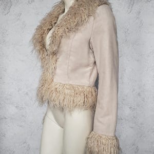 May include: A light beige jacket with a faux fur collar, cuffs, and hem. The jacket is made of a suede-like material and has a tailored fit. The faux fur trim adds a touch of luxury and texture to the garment.
