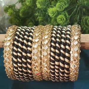 May include: A set of black and gold bangles with a striped pattern and mirror embellishments.