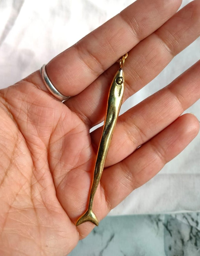 Op de afbeelding: Een gouden vis-hangerketting. De hanger is gedetailleerd en heeft een textuur.