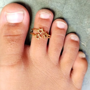 May include: Gold toe ring with three star-shaped charms.