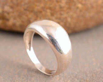 May include: A silver ring with a smooth, rounded, domed top.