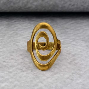 May include: A gold-toned ring with a spiral design. The ring is made of metal and has a smooth finish.