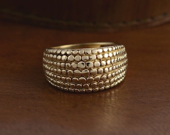 May include: A gold ring with a textured surface. The ring is made of small, round beads that are arranged in a pattern.