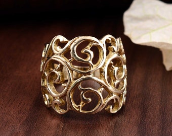 Puede incluir: Un anillo de filigrana dorado con un diseño delicado e intrincado. El anillo está hecho de un metal fino y tiene una banda ancha.