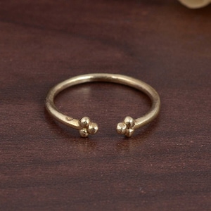 May include: A simple gold ring with two small clusters of three round beads on each side.