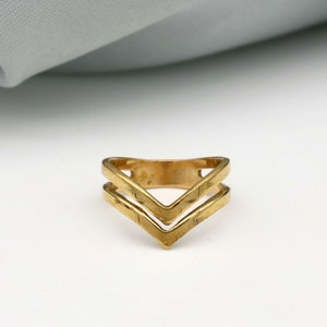 May include: A gold-toned double chevron ring. The ring is made of two overlapping chevron shapes.
