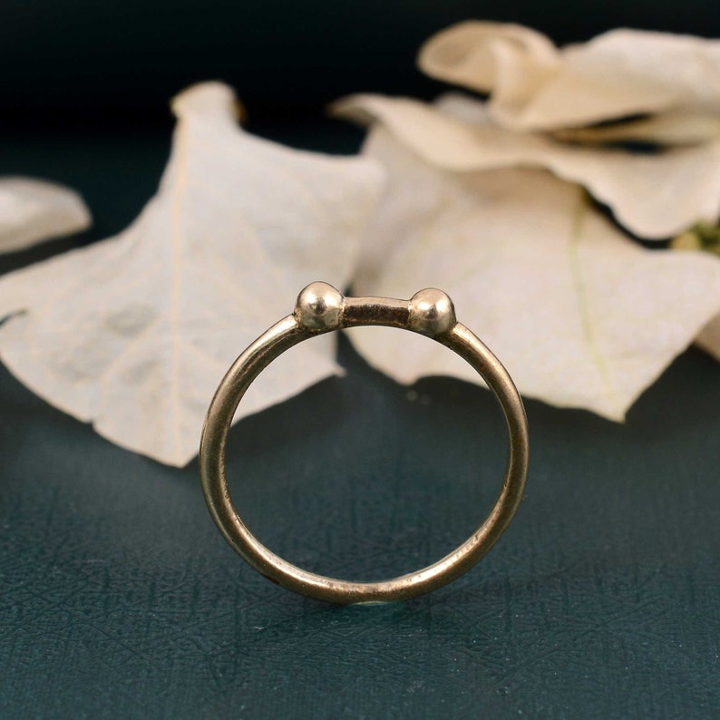 May include: A silver ring with two small round balls on either side of a thin band.