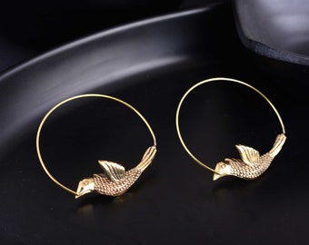 May include: A pair of gold hoop earrings with a bird design. The earrings are made of metal and have a simple, elegant design.