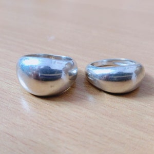 May include: Two silver dome-shaped rings. The rings are smooth and shiny.