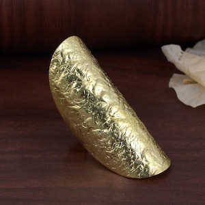 Op de afbeelding: Een gouden, getextureerde, halve cirkelring. De ring is gemaakt van metaal en heeft een gehamerde afwerking.