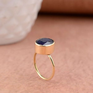 May include: A gold ring with a dark blue oval gemstone set in a bezel setting.