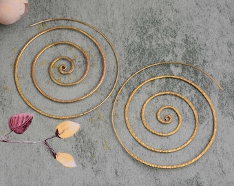 May include: A pair of gold-toned spiral hoop earrings. The earrings are made of thin wire and have a hammered texture.