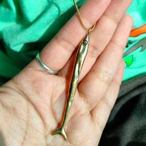 Op de afbeelding: Een gouden vis-hangerketting met een gedetailleerd ontwerp. De hanger hangt aan een gouden ketting.