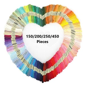May include: A heart-shaped arrangement of colourful embroidery floss spools. The spools are arranged in rows, with the colours transitioning from light to dark. The text "150/200/250/450 Pieces" is printed in the centre of the image.