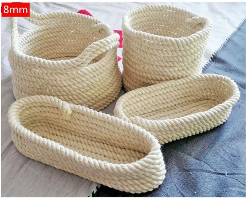 May include: Four natural-colored rope baskets, two oval and two round, with one round basket featuring a handle. The baskets are made of thick, woven rope and are perfect for storage or display.