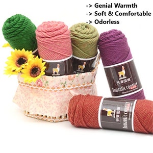 May include: Five skeins of yarn in different colors, including green, pink, olive green, purple, and orange, are arranged in a basket. The yarn is labeled "Romantic Country" and features a llama logo. The text "Genial Warmth", "Soft & Comfortable", and "Odorless" is displayed above the yarn.