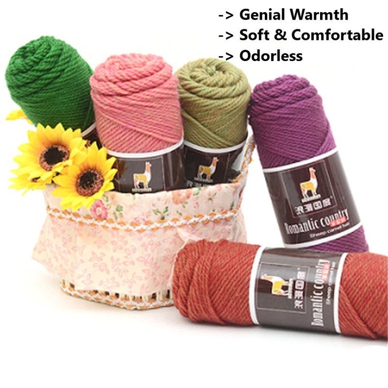 May include: Five skeins of yarn in different colors, including green, pink, olive green, purple, and orange, are arranged in a basket. The yarn is labeled "Romantic Country" and features a llama logo. The text "Genial Warmth", "Soft & Comfortable", and "Odorless" is displayed above the yarn.