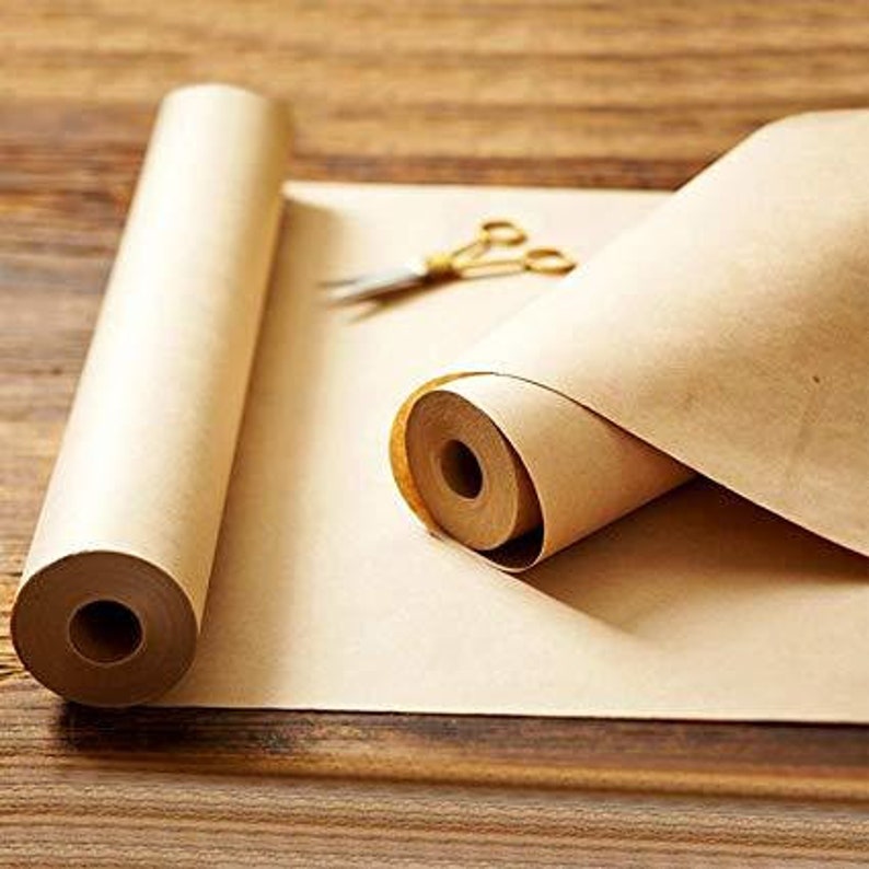 K&ouml;nnte beinhalten: Eine Rolle braunes Bastelpapier ist auf einer Holzoberfl&auml;che ausgerollt. Das Papier ist an beiden Enden aufgerollt, wobei ein Ende teilweise ausgerollt ist. Das Papier ist naturbraun und hat eine leicht strukturierte Oberfl&auml;che.