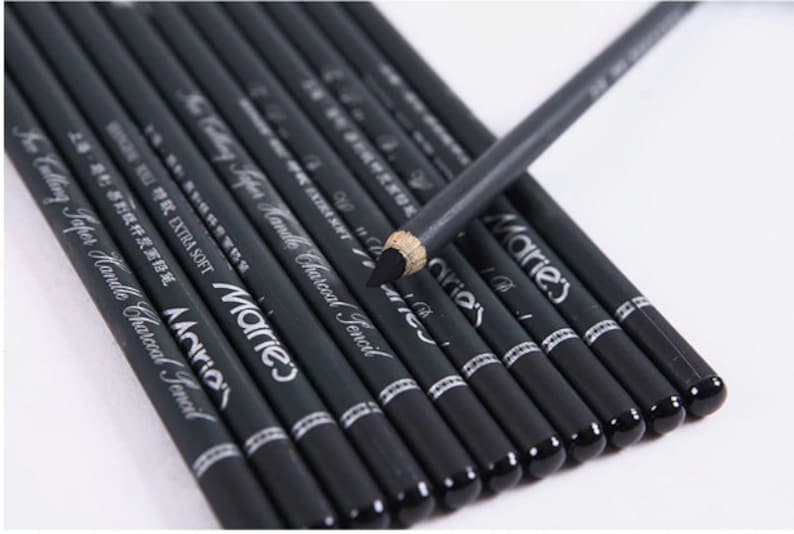 Pu&ograve; includere: Un set di matite di carbone nero con lettere argentate che recitano "Marie's Calling Taper Handle Charcoal Pencil" e "EXTRA SOFT".