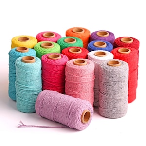 May include: A collection of spools of colorful cotton twine, arranged in a heart shape. The spools are made of cardboard and have a natural brown finish. The twine is available in a variety of colors, including red, blue, green, yellow, and purple.